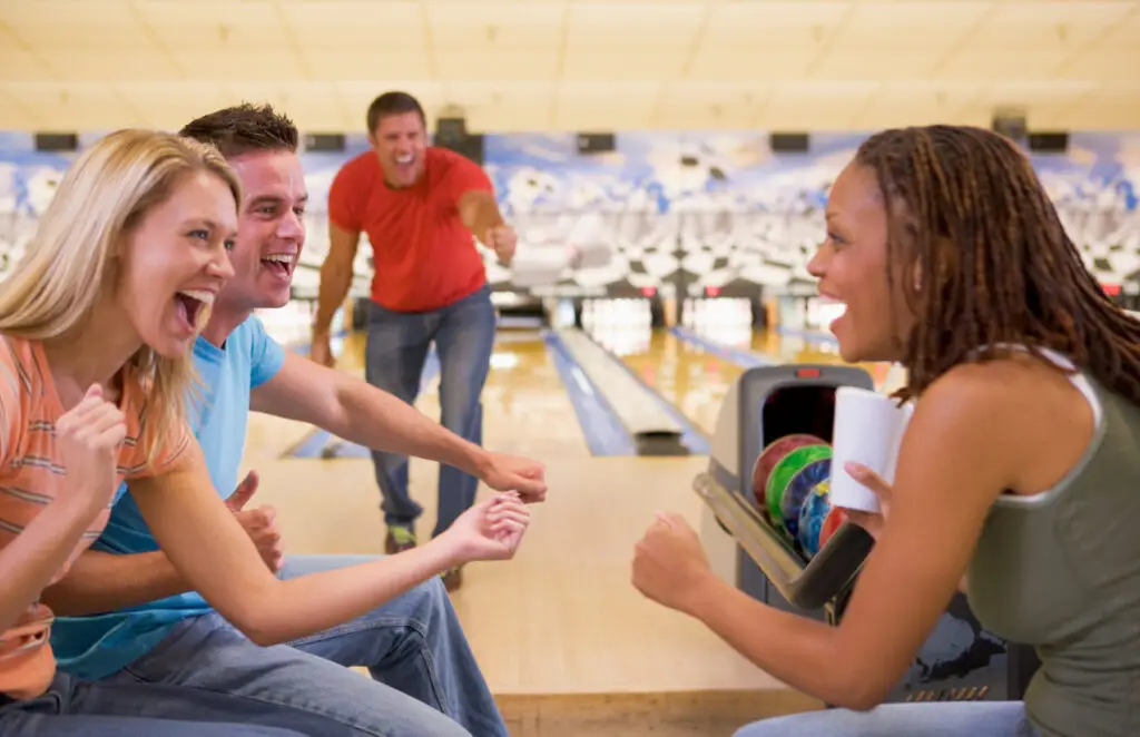 Four young adults cheering in a bowling alley